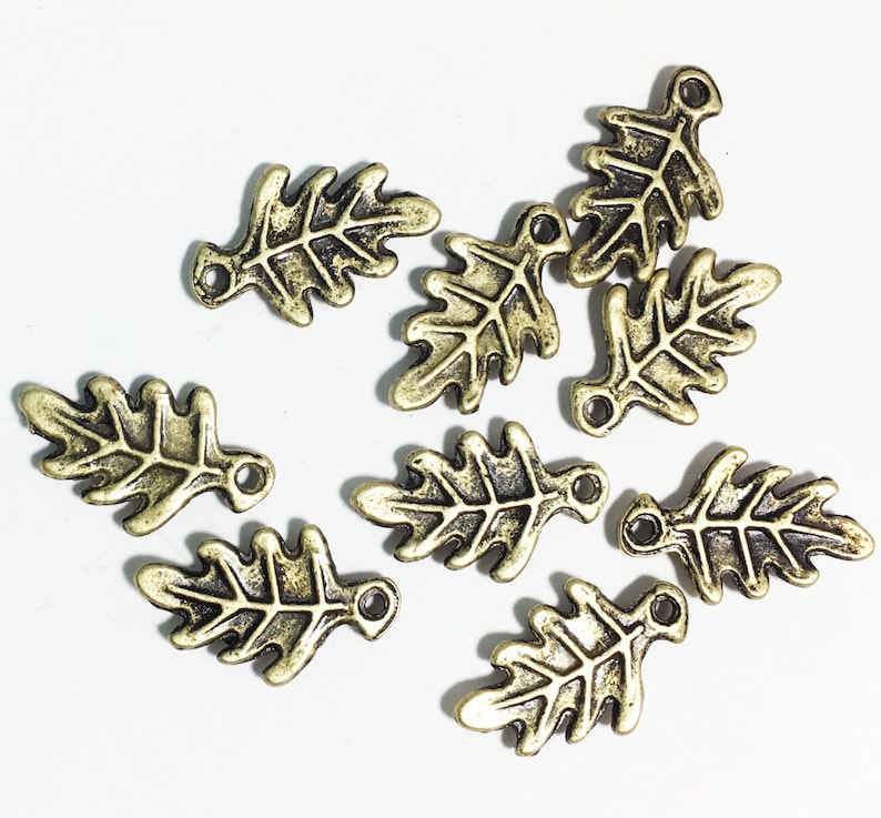 K&ouml;nnte beinhalten: Zehn antike goldfarbene Metall-Bl&auml;tter-Anh&auml;nger mit detailliertem Design. Jeder Anh&auml;nger hat eine kleine &Ouml;se zum Anbringen an Schmuck oder andere Bastelarbeiten.