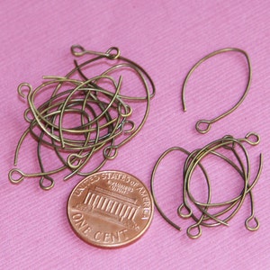 May include: A pile of 18 gauge bronze wire earring hooks, next to a US penny for size comparison. The hooks are approximately 1 inch long.
