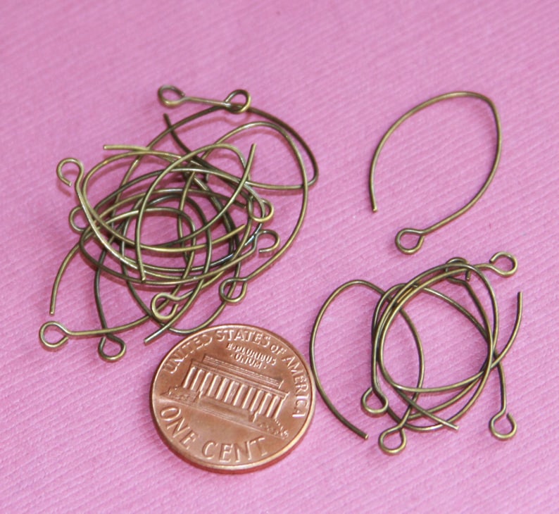 May include: A pile of 18 gauge bronze wire earring hooks, next to a US penny for size comparison. The hooks are approximately 1 inch long.