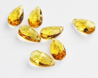 May include: Seven amber teardrop-shaped crystal beads with faceted surfaces.