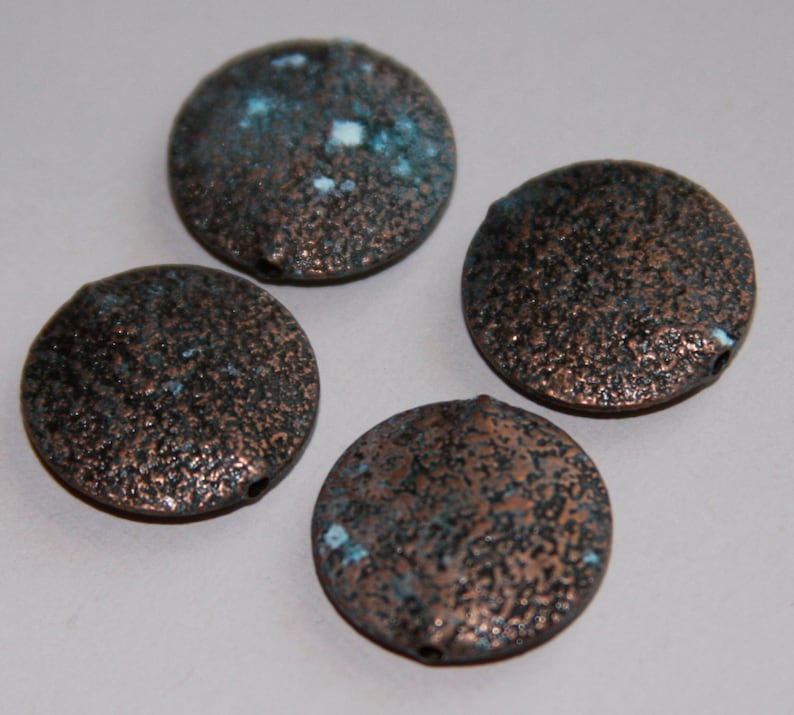 May include: Four round, copper-colored beads with a textured surface and a speckled blue and white glaze.