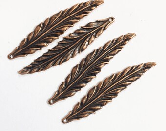 May include: Four antique copper-colored metal leaf-shaped charms with a hole at the top for hanging.