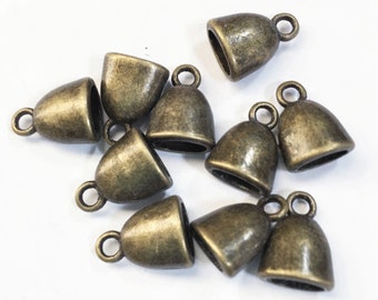 May include: Ten antique gold-toned metal cord end caps with a loop opening. The caps are shaped like a bell with a rounded top and a flat bottom.
