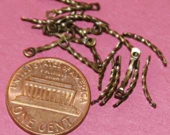 May include: A pile of small, twisted, gold-colored metal pieces with loops at each end. The pieces are about the size of a US penny.
