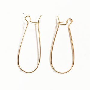 Op de afbeelding: Een paar gouden oorbelsluitingen in druppelvorm.