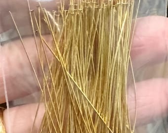 Pode incluir: Um saco plástico transparente cheio de numerosos alfinetes dourados. Os alfinetes têm um eixo reto e fino e uma pequena cabeça arredondada. Os alfinetes estão bem embalados, criando um feixe denso.
