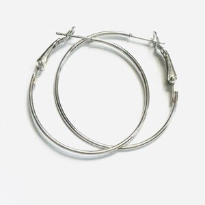 May include: A pair of silver hoop earrings with a hinged clasp.