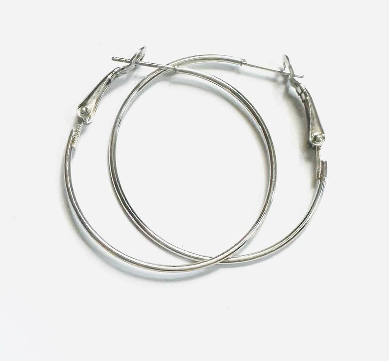 May include: A pair of silver hoop earrings with a hinged clasp.