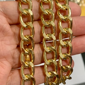 Könnte beinhalten: Drei goldene Ketten mit einem strukturierten, flachen, ovalen Glieddesign. Die Ketten liegen nebeneinander und zeigen die Details der Glieder.