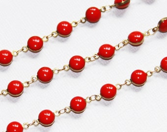 May include: A gold chain necklace with red round beads. The necklace is made of metal and has a simple design.