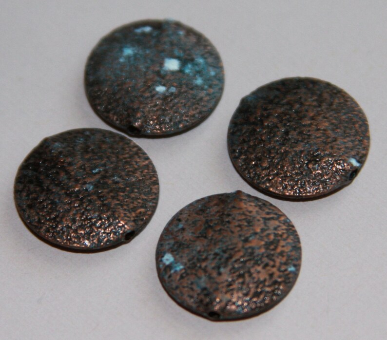 May include: Four round copper-colored beads with a textured surface and blue and white accents.
