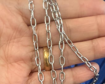 Op de afbeelding: Een zilveren ketting met meerdere strengen ovale schakels. De ketting wordt getoond in een hand, met een gouden ring aan een van de vingers.