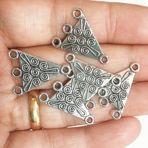 May include: Five silver triangle-shaped metal connector charms with a swirl design. Each charm has three holes for attaching jewelry.
