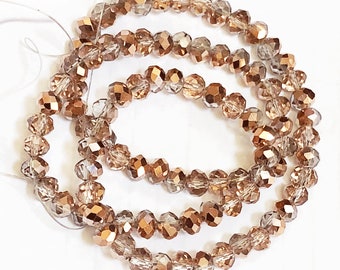 May include: A strand of copper-colored glass beads with a faceted finish. The beads are strung on a clear thread and are arranged in a circular pattern.