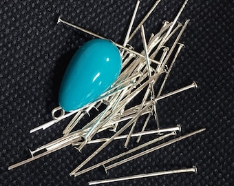 Puede incluir: Un montón de alfileres de cabeza plateados con una cuenta de forma de lágrima azul turquesa en la parte superior.