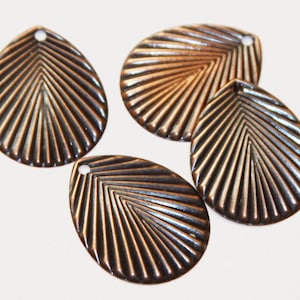 May include: Four copper-colored metal leaf-shaped charms with a textured design. Each charm has a small hole at the top for attaching to jewelry or other crafts.