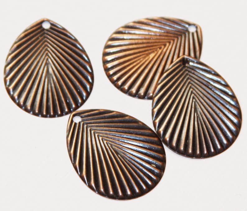 May include: Four copper-colored metal leaf-shaped charms with a textured design. Each charm has a small hole at the top for attaching to jewelry or other crafts.