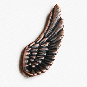 May include: A single copper-colored angel wing charm with a hole for attaching to a necklace or bracelet. The wing is detailed with a textured surface and a realistic design.