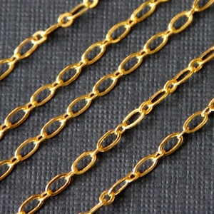May include: Four strands of gold chain with oval links. The chain is on a dark gray textured surface.