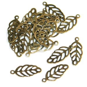 May include: A collection of antique bronze-colored metal leaf charms, each featuring a delicate filigree cutout design with a small circular loop at the top for attachment. These small, lightweight jewelry components are arranged in a cluster.