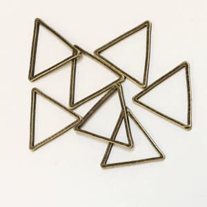 May include: A group of six antique gold triangle shaped metal rings. The rings are all the same size and shape, and they are arranged in a random pattern.