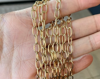 May include: A close-up of a gold chain with multiple strands. The chain is made of oval-shaped links.