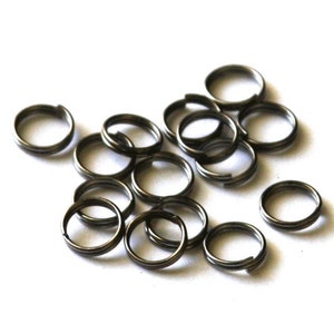 May include: A pile of 15 silver-toned metal key rings. The rings are all the same size and are arranged in a random pattern.