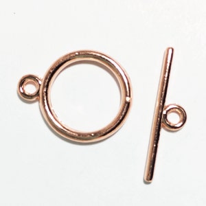 May include: Rose gold toggle clasp with a round ring and a straight bar. The clasp is a jewelry finding used to secure necklaces, bracelets, and other jewelry.