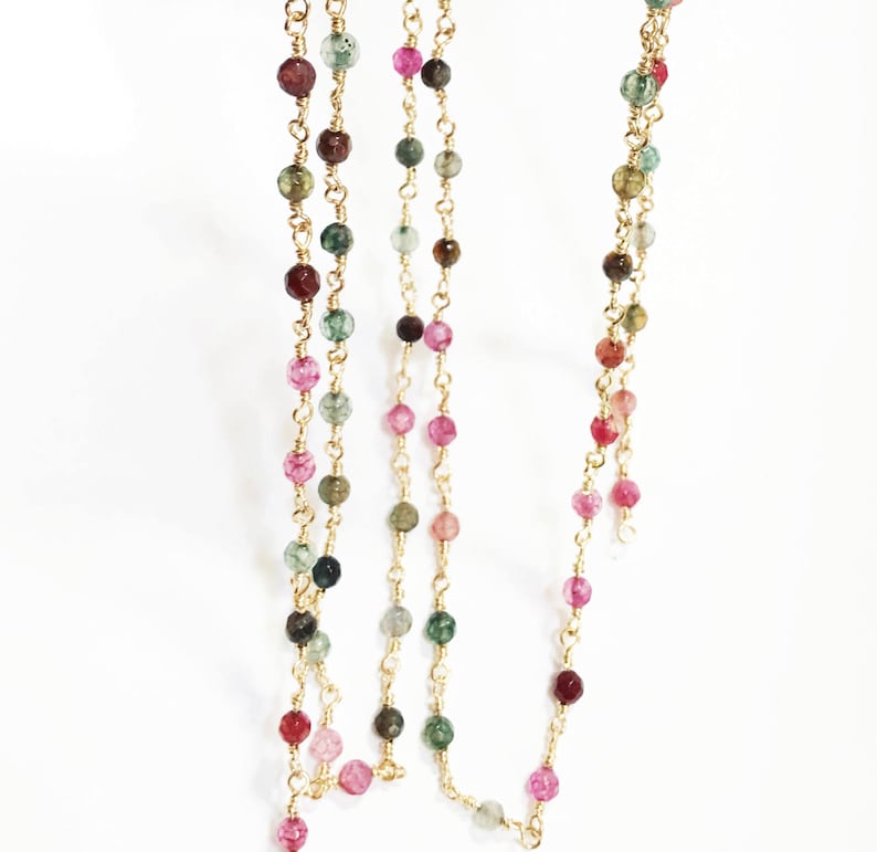 May include: A gold chain necklace with multi-colored beads. The beads are a mix of pink, green, and brown.