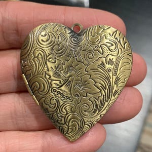 Antiqued brass extra large 42mm heart locket pendants with intricate floral designs on a plain white background.