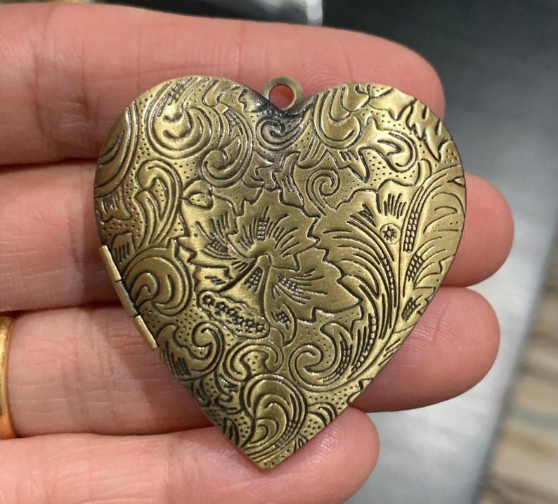 Antiqued brass extra large 42mm heart locket pendants with intricate floral designs on a plain white background.