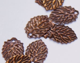May include: A group of small, antique gold-toned metal leaf charms with a textured surface. The leaves have a hole at the top for attaching to jewelry or other crafts.