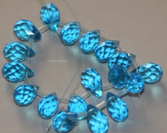 May include: A strand of faceted teardrop-shaped beads in a bright turquoise blue color. The beads are strung on a clear elastic cord.