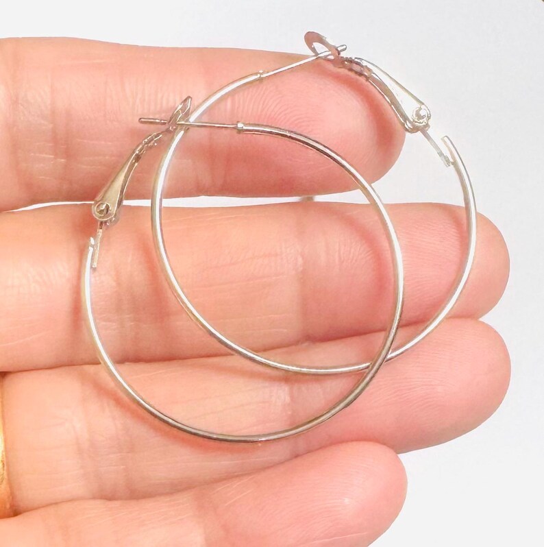 May include: A pair of silver hoop earrings with a hinged clasp.