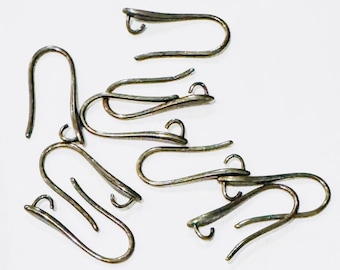 May include: A group of silver-toned earring hooks, also known as ear wires, are scattered on a white surface. The hooks are made of metal and have a simple, elegant design.