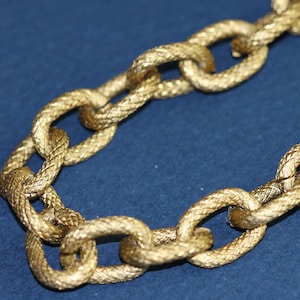 May include: A gold chain necklace with a woven texture. The chain is made of linked ovals.