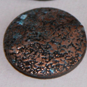 May include: A round, copper-colored bead with a textured surface. The bead has a dark blue and green patina.