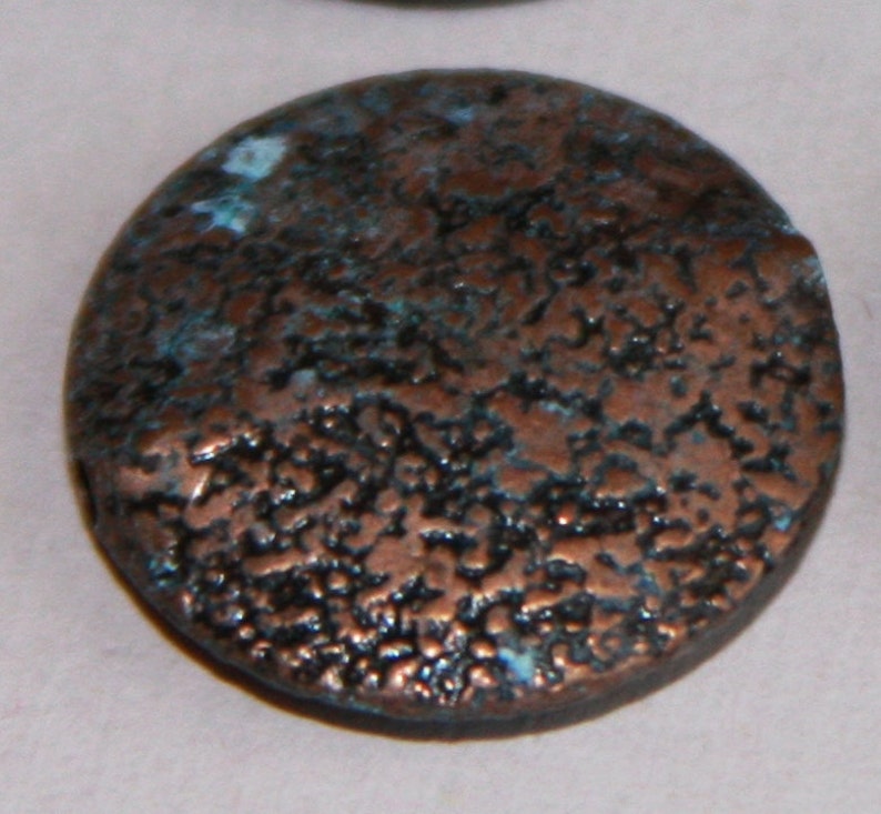 May include: A round, copper-colored bead with a textured surface. The bead has a dark blue and green patina.