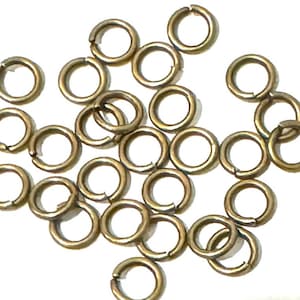 May include: A large quantity of gold jump rings, which are small metal rings used for connecting jewelry components.