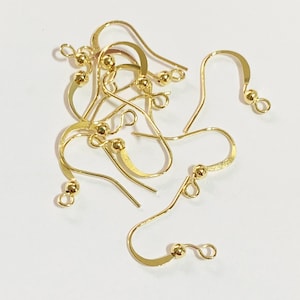 May include: A group of gold-toned earring hooks with small round balls at the top. The hooks are made of metal and are designed for attaching earrings.