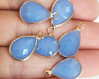 May include: Five light blue teardrop-shaped gemstone pendants with gold-toned metal settings and jump rings.