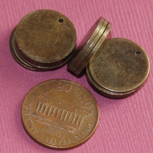 以下が含まれることがあります： 中央に小さな穴が開いた真鍮色の丸い金属製の円盤が3枚。円盤は互いに積み重ねられています。手前に1セント硬貨があります。