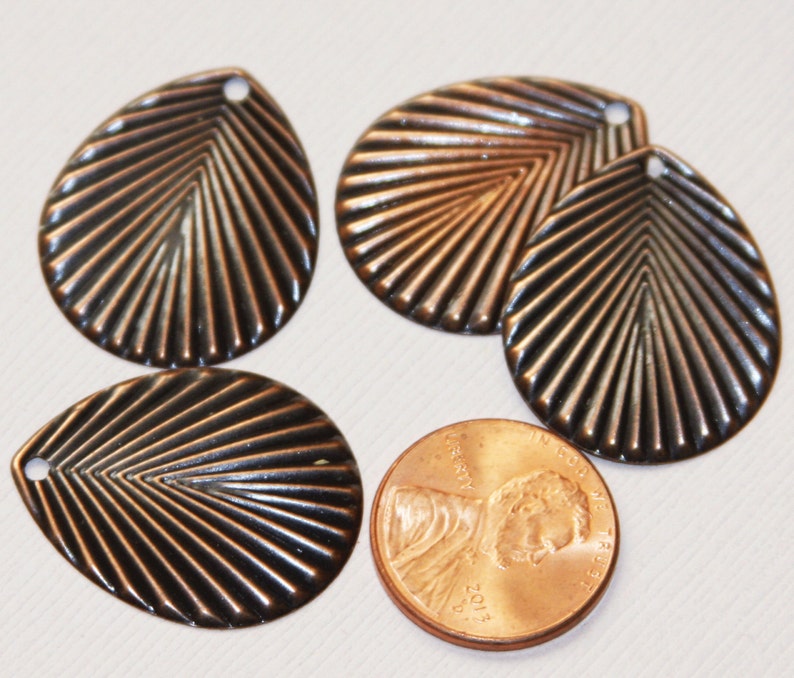 May include: Four copper-colored metal leaf-shaped charms with a ridged design. The charms have a hole at the top for attaching to jewelry or other crafts.