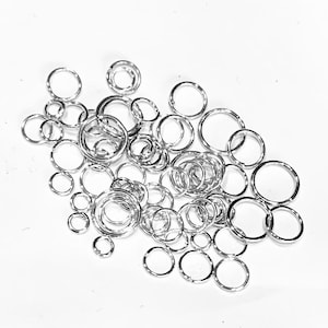 May include: A large pile of silver jump rings of various sizes. The rings are all smooth and shiny.