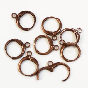 Puede incluir: Ocho aros de pendientes de color cobre con cierre de resorte. Los aros son todos del mismo tama&ntilde;o y est&aacute;n dispuestos en una pila.