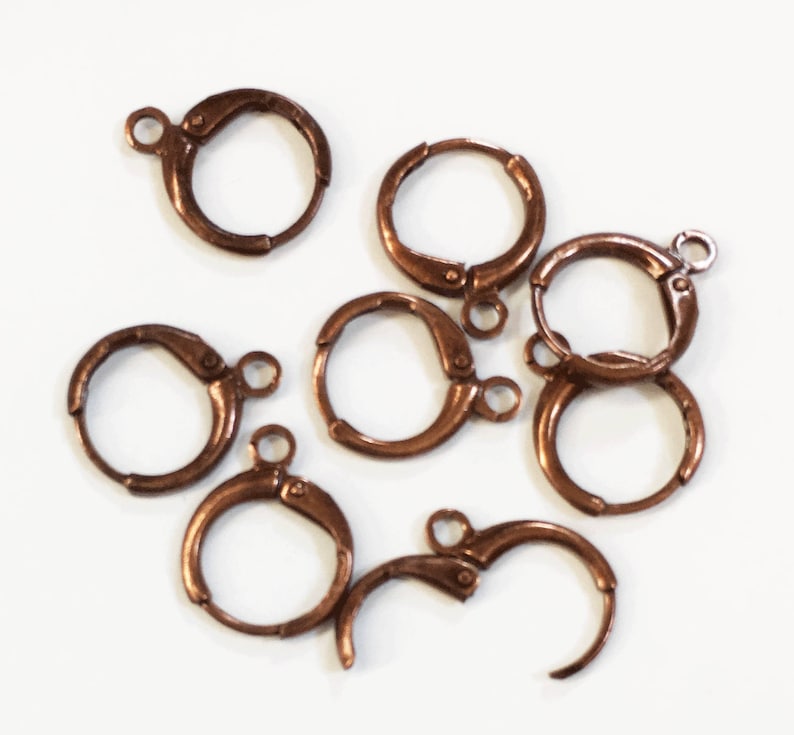 Puede incluir: Ocho aros de pendientes de color cobre con cierre de resorte. Los aros son todos del mismo tama&ntilde;o y est&aacute;n dispuestos en una pila.