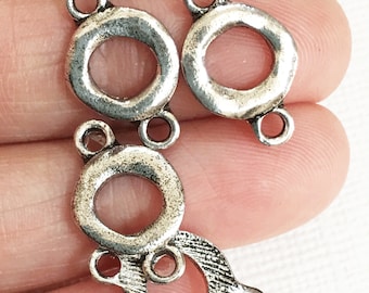 May include: Four silver-toned metal connector charms with three loops each. The charms are round with a textured surface and a hole in the center.