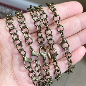 Op de afbeelding: Vier strengen gouden ketting met karabijnhaken. De kettingen zijn gemaakt van kleine, ronde schakels.