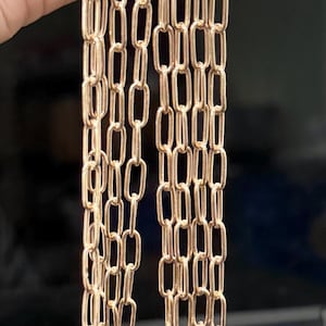 May include: A close-up of multiple strands of gold-colored chain. The chain is made of small, rectangular links.