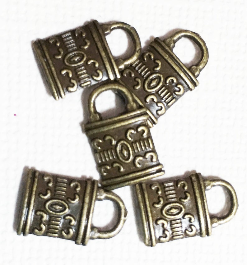 May include: Five antique gold-toned metal lock charms with intricate designs. Each charm has a small loop at the top for attaching to a necklace, bracelet, or other jewellery.